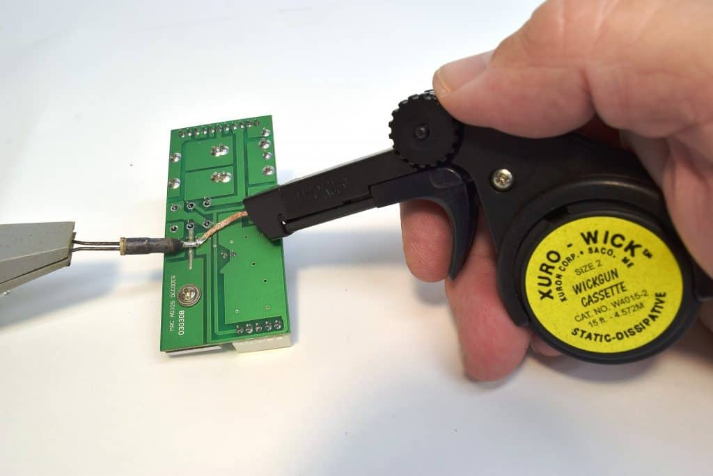 Xuron® WickGun™ Desoldering Braid Dispenser removing solder from a printed circuit board.